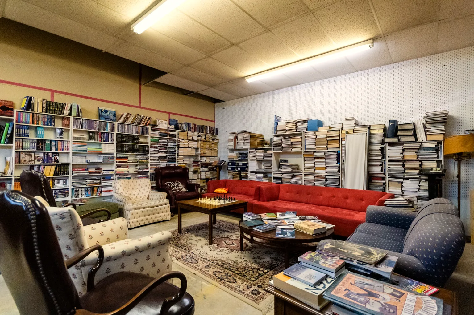The public lounge area at Lucky Dog Books East Dallas, with red couches and a chess table among the bookshelves